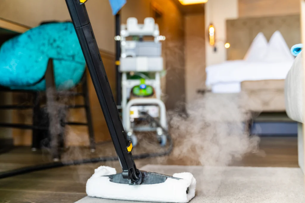 Reinigung des Teppichbodens im Hotelzimmer mit dem Dampfreiniger inklusive Baumwolltuch
